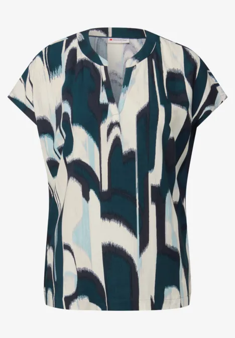 Bluse mit blau-weißen abstrakten Mustern und kurzem Schnitt.